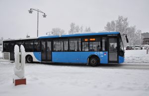 En buss som kör på gatan och snörik landskap.