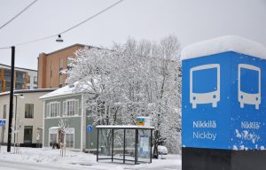 En skylt med text Nickby, gatan och snörik landskap.