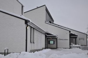 En vit byggnad och snö kring byggnaden.
