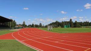 Urheilukenttä, jossa näkyy juoksuratoja, nurmialue ja jalkapallomaali.