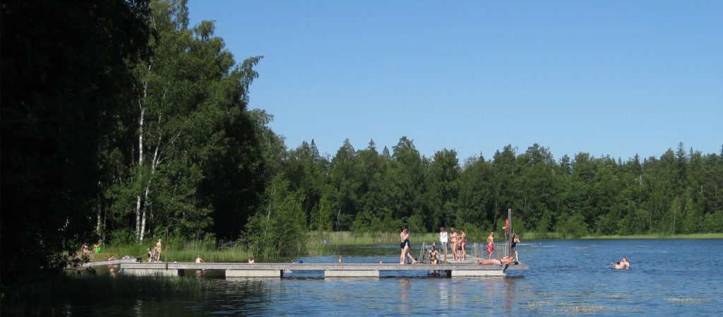 Människor som simmar och solar på Tasträsk brygga