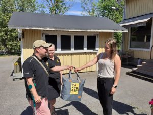 På Krogen Restaurant's owner couple hands a picnic bag to Municipality of Sipoo Business coordinator Anne Peltonen.