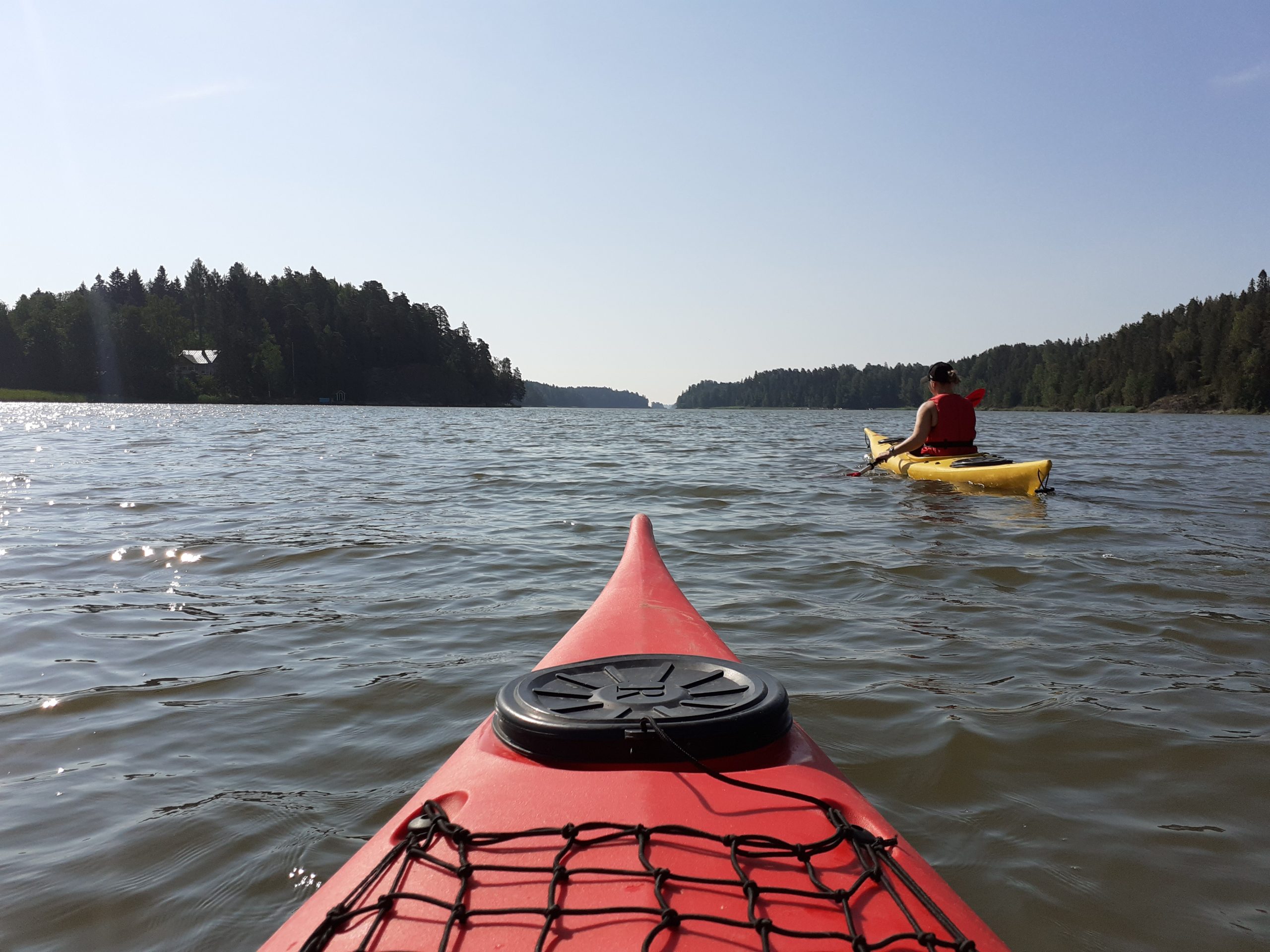 View from a kayak at Sipoo bay, with archipelago and another kayak.