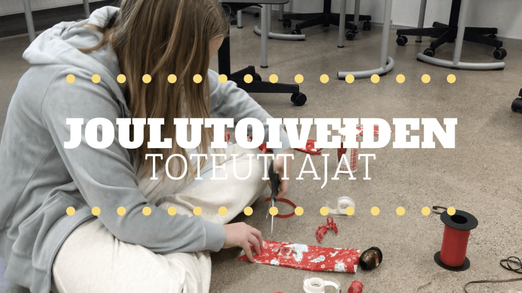 En ungdom sitter på golvet och håller på att paketera en gåva. Text: "Joulutoiveiden toteuttajat".