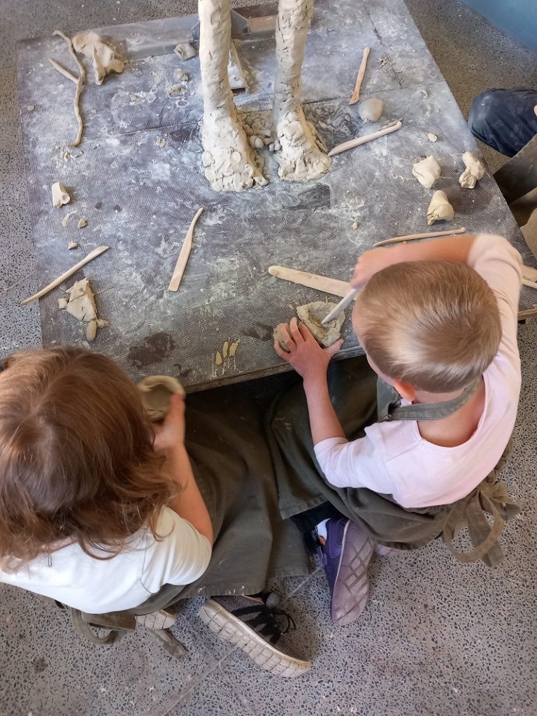 Två barn utarbetar en skulptur.