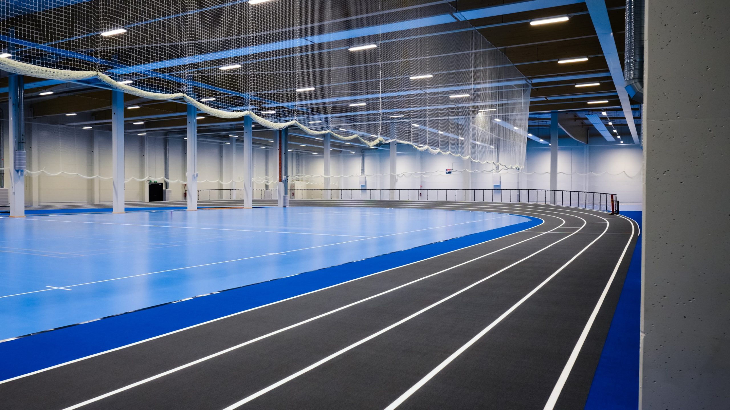 Liikuntahallia sisältä. Juoksuradat kiertävät eri lajeihin sopivaa kenttää.