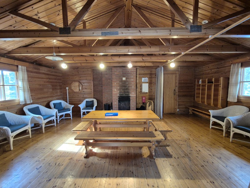 Saunarakennus sisältä, keskellä pöytäryhmä ja sivulla tuoleja