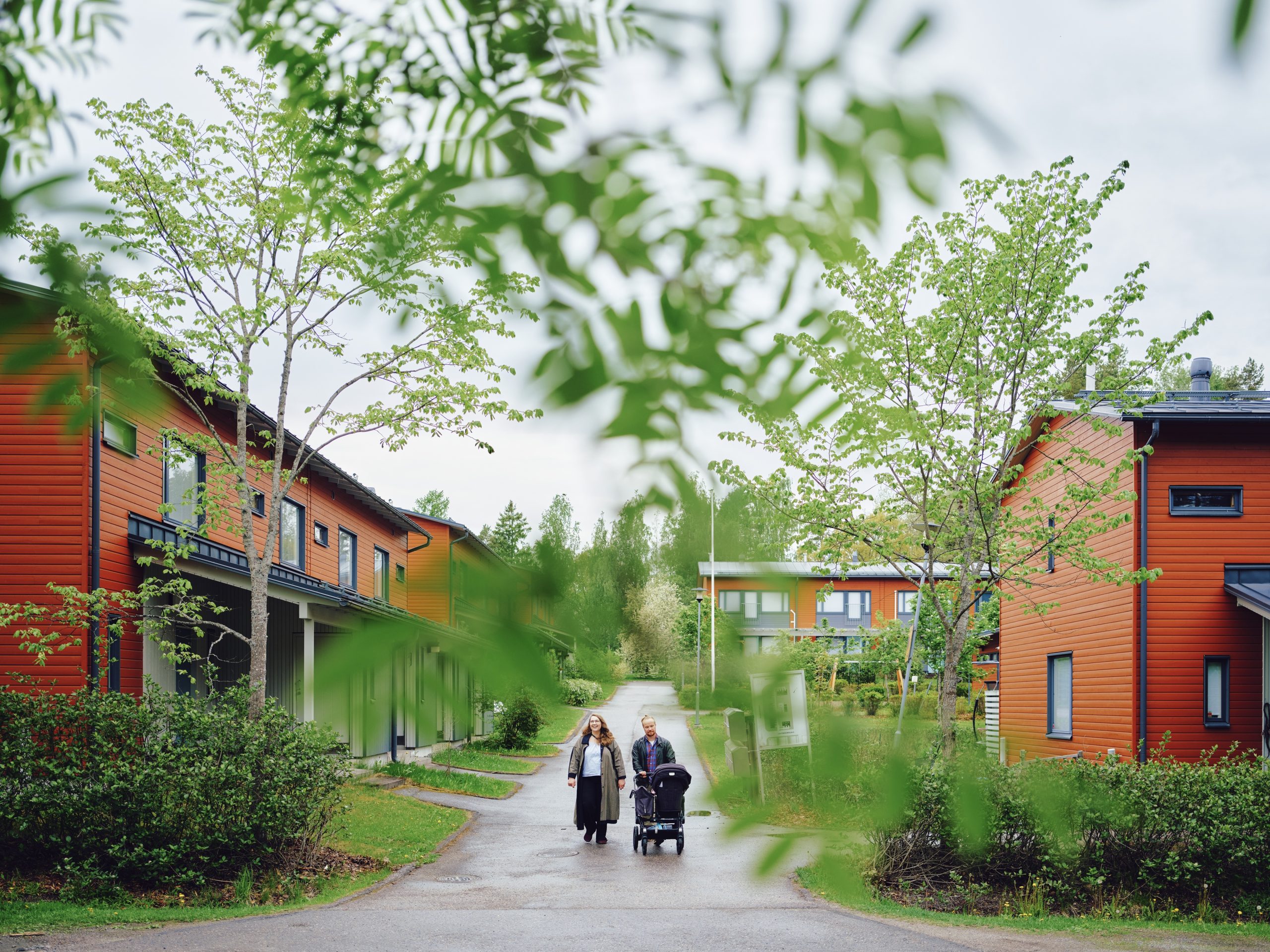 Taru ja Eetu Sairanen kävelevät vaunujen kanssa rivitalojen reunustamalla vehreällä kävelytiellä.