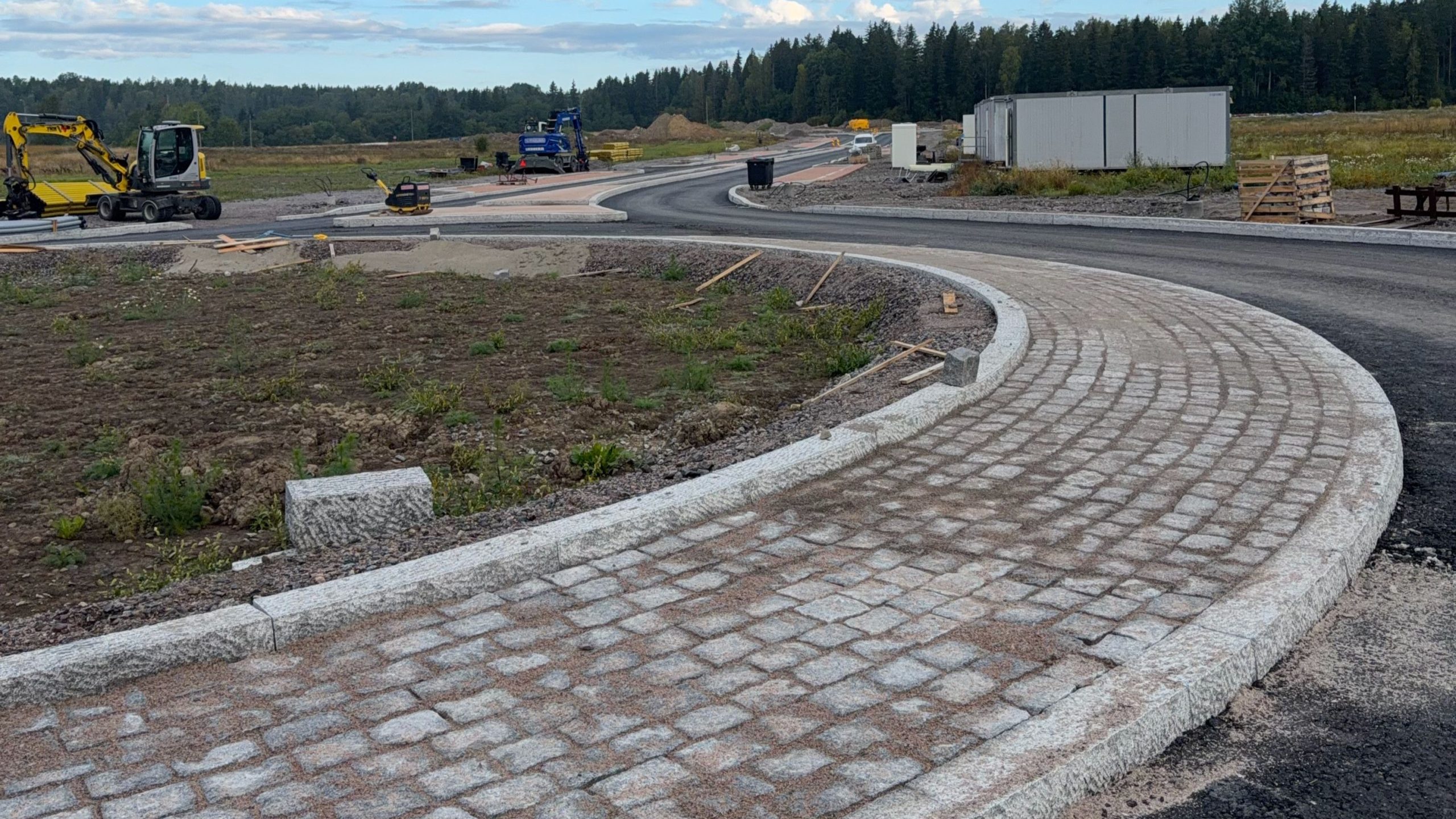 Kadun pintarakenteita rakennetaan työmaalla. Asfalttia, kivetyksiä, työkoneita.